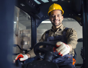 Portrait smiling caucasian forklift operator driving machine working storehouse - Kézi anyagmozgató és targoncavezető